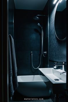 Dimly lit modern bathroom with a round mirror, bathtub, and sleek sink.