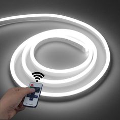 a hand holding a remote control in front of a circular light with wifi on it