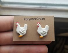 a pair of small white chicken earrings on a brown card with the word polymer craze written below it