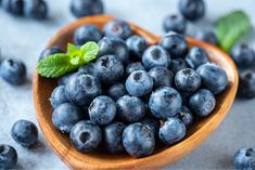 a wooden spoon filled with blueberries on top of a table