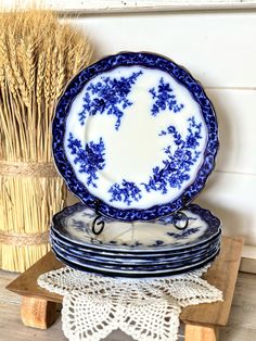 blue and white plates stacked on top of each other in front of a basket with wheat stalks