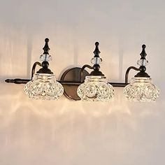 three light bathroom fixture with clear glass shades and black metal fittings on the wall