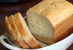 a loaf of bread sitting on top of a white bowl next to slices of bread