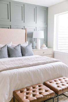 a white bed sitting in a bedroom next to a window with shutters on it