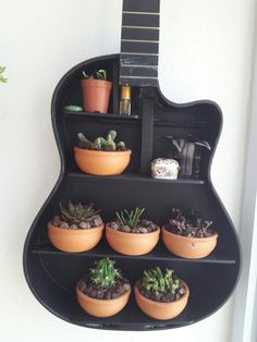 a guitar shaped shelf with potted plants on it