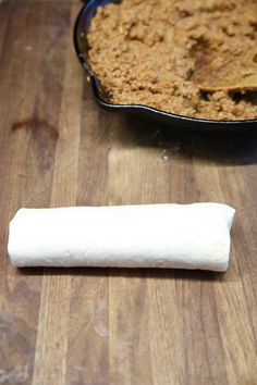 a piece of bread sitting on top of a wooden cutting board next to a bowl