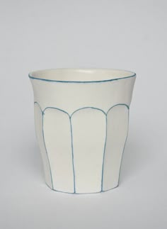 a white and blue cup with lines on the rim, sitting against a gray background