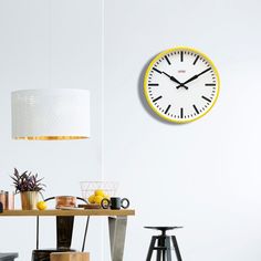 a clock on the wall above a table with chairs and stools in front of it