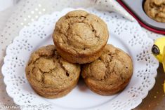 three muffins on a white plate next to a banana and cupcake tin