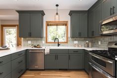 a kitchen with gray cabinets and stainless steel appliances