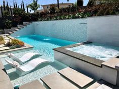 an outdoor hot tub next to a pool with lounge chairs on the side and steps leading up to it