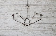 a metal hook hanging from the side of a white wooden wall with two hooks attached to it