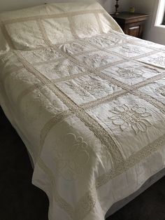 the bed is made with white linens and has a quilted design on it