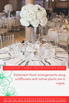 the table is set with white flowers and place settings