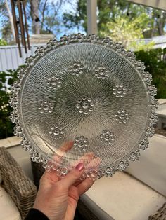 a person holding up a glass plate with beading on it's rims