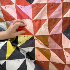 a person is cutting fabric with scissors and sewing needles on a piece of cloth that has been made into a quilt