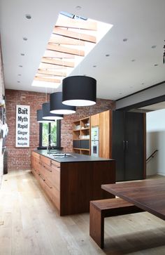 an open kitchen with wooden floors and brick walls, along with a skylight over the island