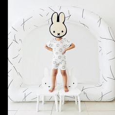 a little boy standing on two stools in front of an inflatable bunny