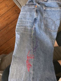 someone is showing off their jean pants with embroidered designs on them