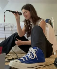 a woman sitting on the floor with headphones in her ears and listening to music