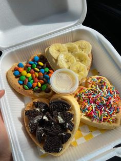 a person is holding a container with some food in it, including bananas and cookies