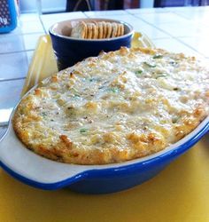 a blue and white plate topped with food next to a bowl filled with crackers