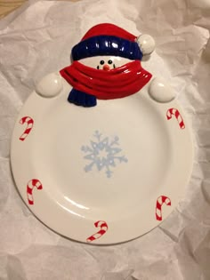 a plate with a snowman on it and candy canes in the bottom corner