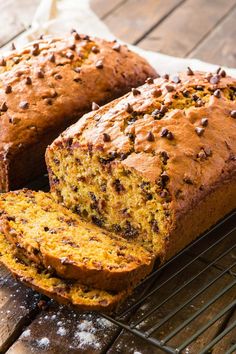 a loaf of chocolate chip banana bread sitting on top of a cooling rack next to a slice cut from it