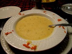 a white bowl filled with soup sitting on top of a table next to silverware