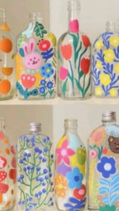 there are many colorful glass bottles on the shelf together, each with different designs and colors