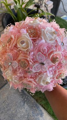 a bridal bouquet with pink and white flowers in the middle is being held by someone's hand