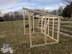 a wooden structure sitting in the middle of a grass covered field next to a fence