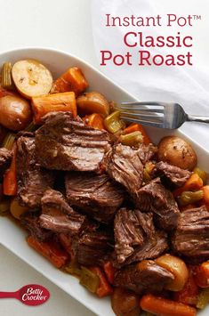 a white bowl filled with roast and vegetables on top of a table next to a fork