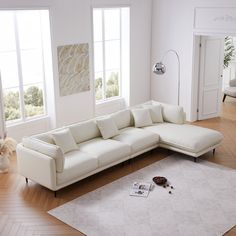 a living room with white furniture and wood flooring, including a large sectional sofa