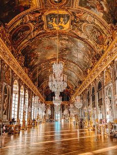 an ornate hall with chandeliers and paintings on the walls