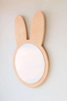 a wooden mirror with an animal's ears on it and a white wall in the background