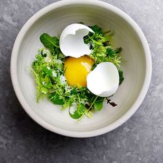 an egg and greens in a white bowl