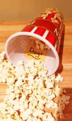 popcorn spilled out of a red and white cup on a wooden table with the word dog written in it