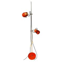 an orange floor lamp with two red lamps on it's sides and a white background