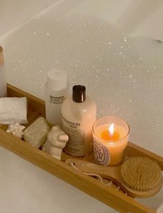 a bathtub filled with lots of different types of soaps and lotions next to a candle