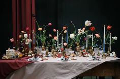 a table topped with lots of vases filled with different types of flowers and candles