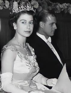 an old black and white photo of a woman in a tiara with a man standing behind her