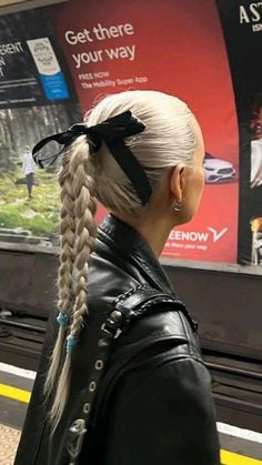 a woman with blonde hair wearing a black leather jacket and braids on her head