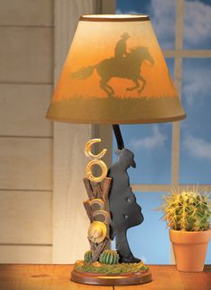 a lamp with a horse and rider on it sitting on a table next to a potted plant