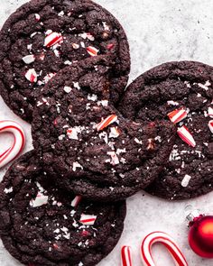 chocolate cookies with candy canes and peppermints on a white surface next to christmas decorations