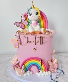 a pink cake with a unicorn on top and butterflies around the edges that say charlotte