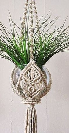 a plant hanging from the ceiling with beads and grass in it's centerpiece