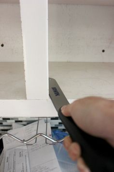 a person is holding a pair of scissors in front of some papers on a shelf