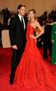 a man and woman in formal wear posing on the red carpet at an event with cameras