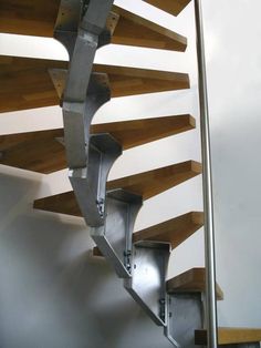 a metal spiral staircase in a building with wood and steel railings on the sides